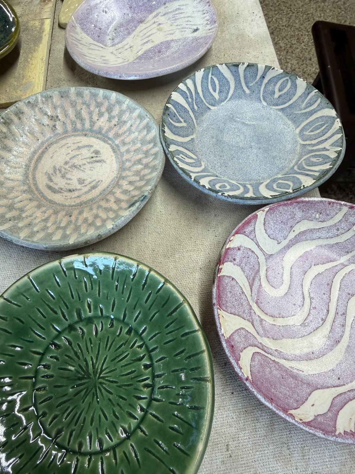 Hand-carved plates finished in green, blue, and pink glazes