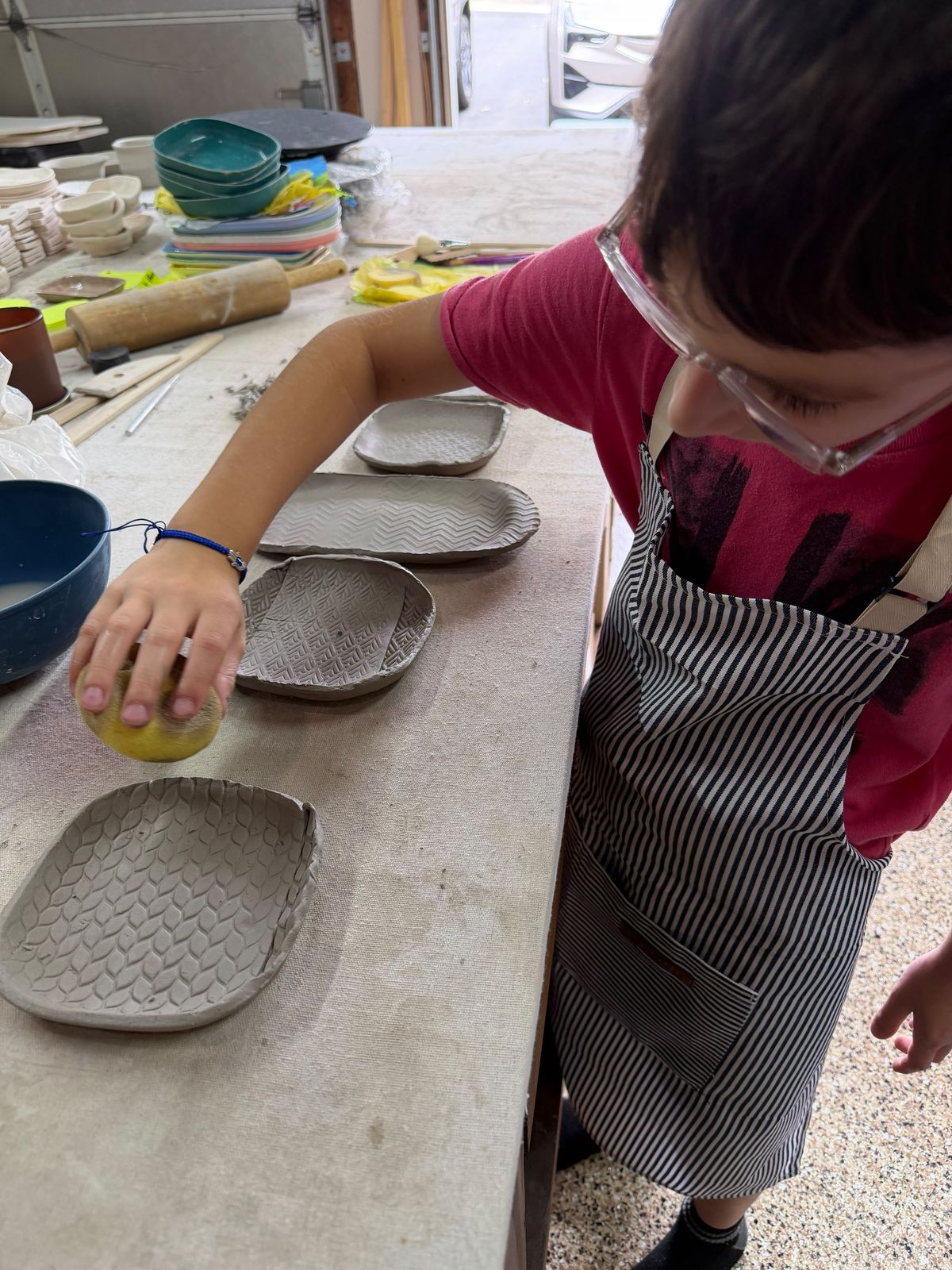 Young student smoothing stamped clay plates at the studio