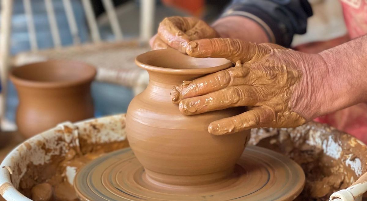 Shaping a clay vase by hand on the wheel