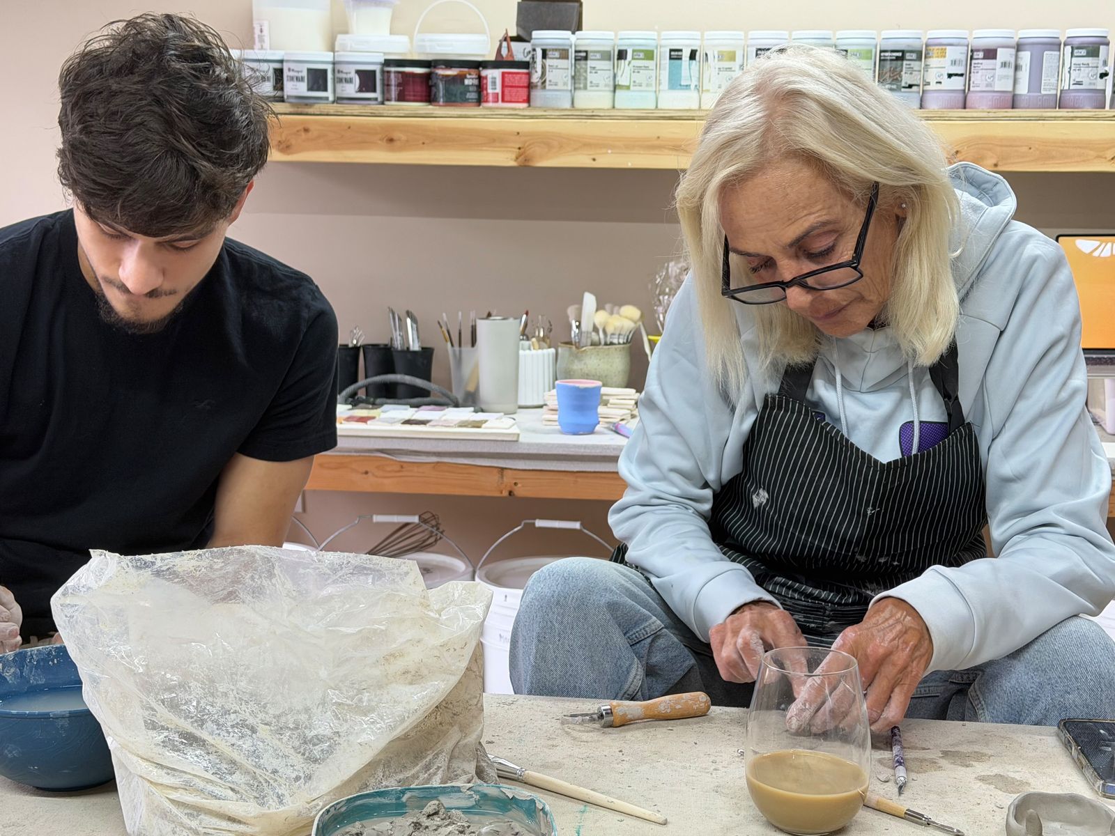 Students working on clay pieces at the Second Fire Studio worktable